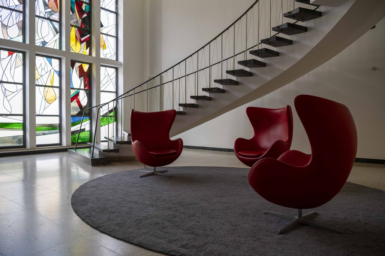 LÜCHTENHOF - Foyer mit roten Sesseln, bunten Fenstern und Treppenaufgang
