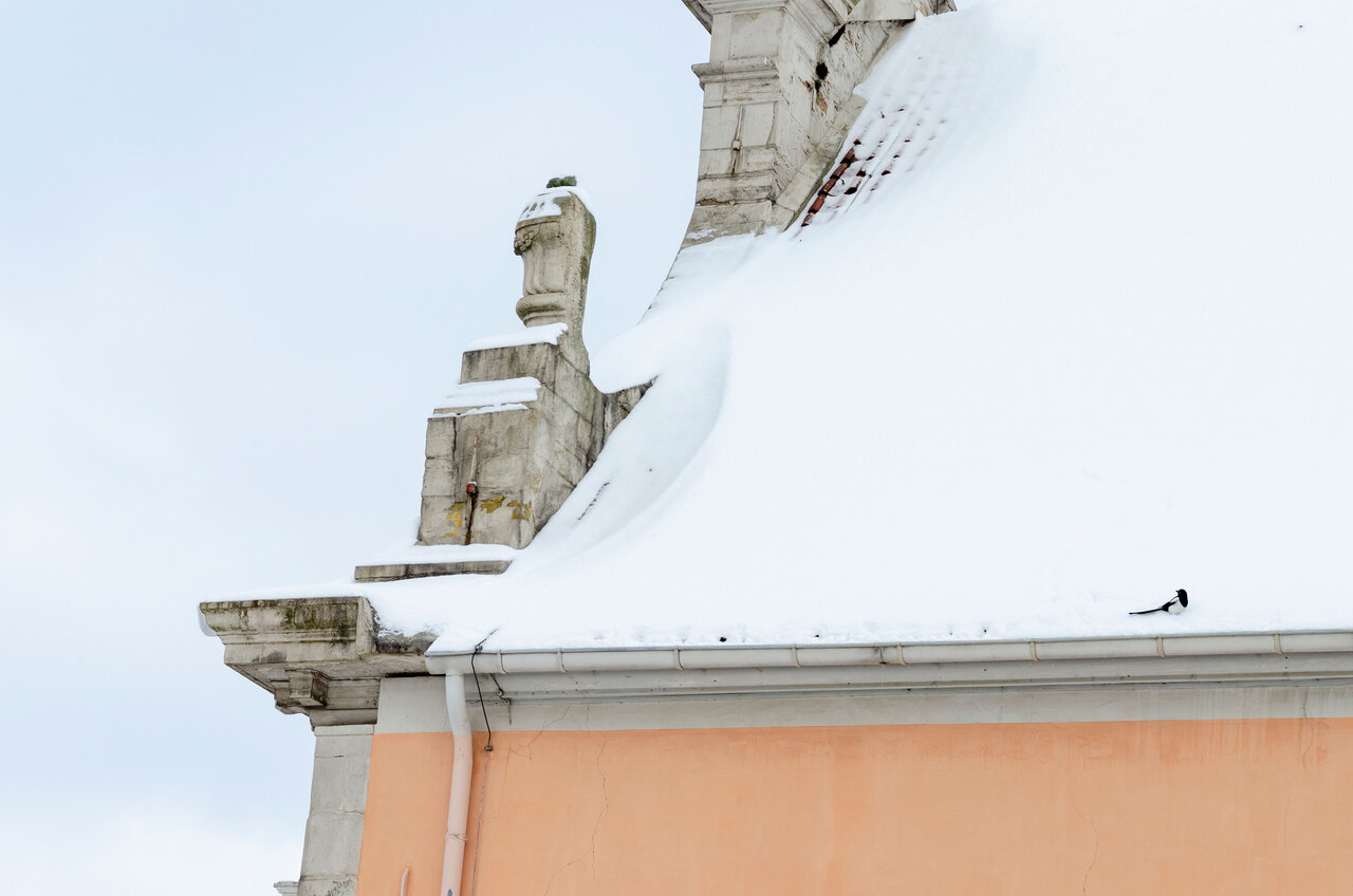 LÜCHTENHOF - Schneebdecktes Dach der Kirche mit einer sitzenden Elster