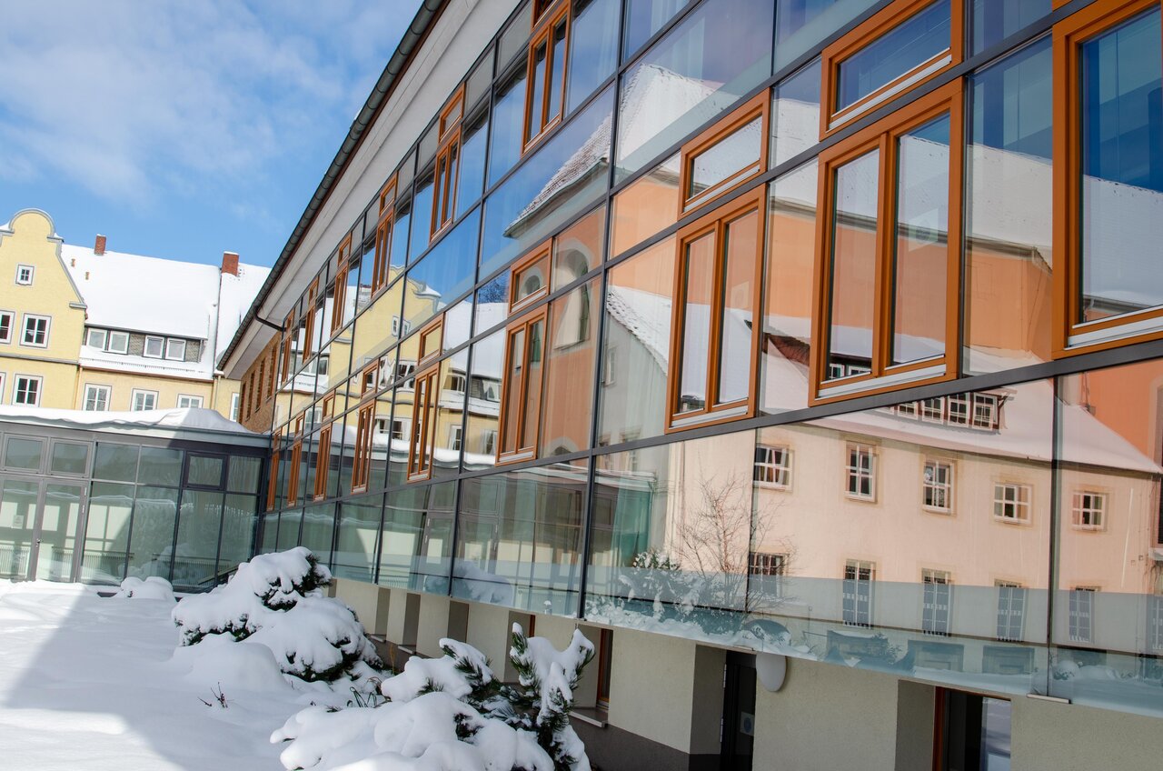 LÜCHTENHOF - Schneebdeckter Hofgarten - Altbau, der sich im gläsernen Neubau spiegelt