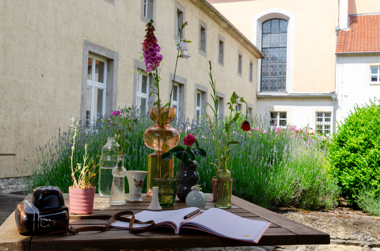 LÜCHTENHOF - Hofgarten - Blick auf Stilleben von Blumen, Buch und Fotoapparat vor Altbau