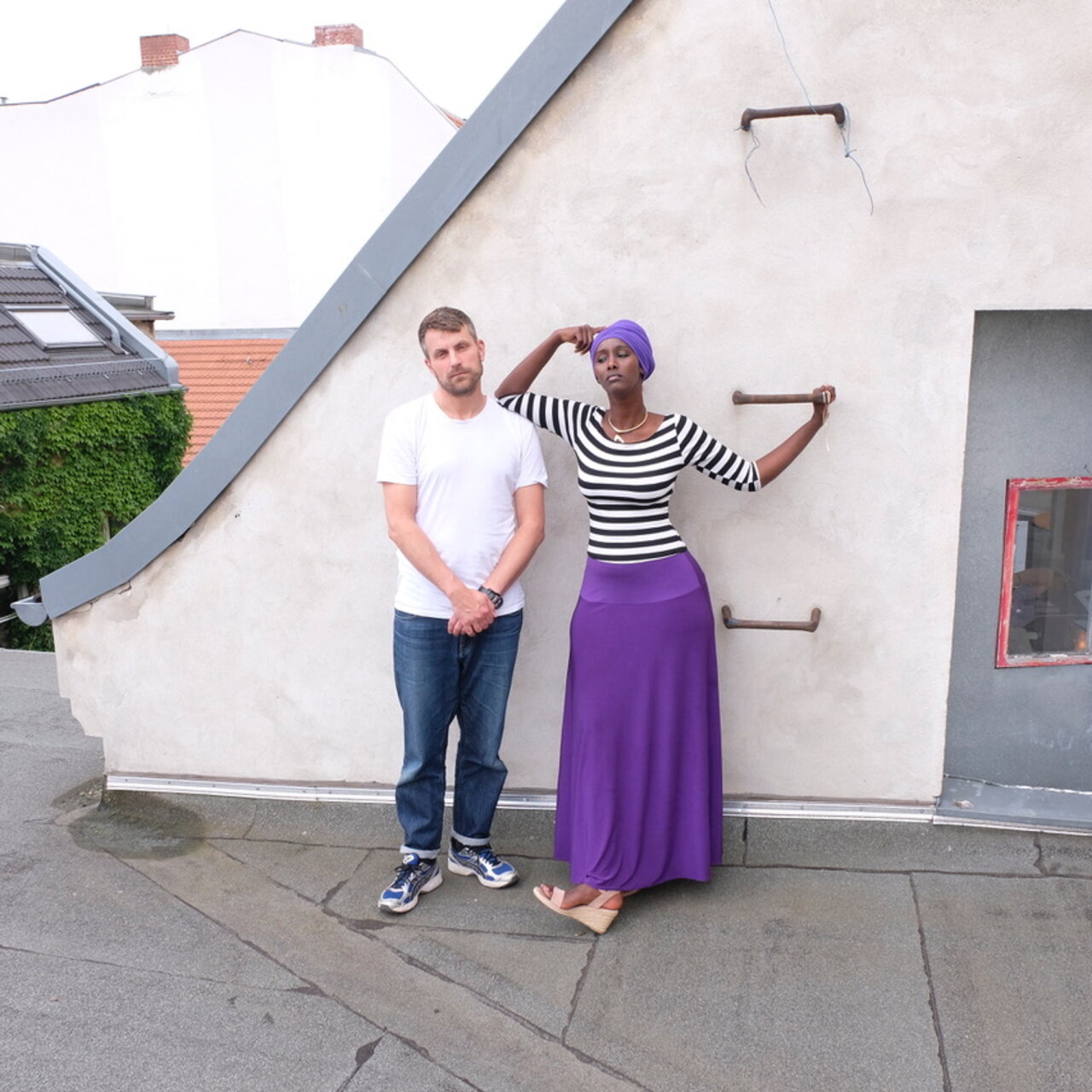 Fatuma Musa Afrah und Jon Hoekstra auf einem Häuserdach an eine Wand gelehnt